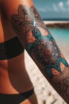 a woman's arm with a turtle tattoo on it and the ocean in the background