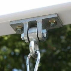 two metal hooks are attached to the side of a white building with trees in the background