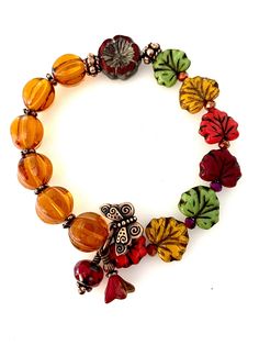 "A colorful fall stretch bracelet featuring premium topaz yellow Czech glass fluted melon beads as mini pumpkins and gorgeous fall colored Czech glass maple leaves in reddish maroon, orange, yellow, and green. Accented with a 15mm red pomegranate Czech glass flower and two antique copper rondelles. Tiny iridescent orange/red Chinese crystals and copper daisies are added for accent. A darling  little antique copper butterfly charm, reddish Picasso beads and little bronzed pomegranate bellflower a Bohemian Adjustable Jewelry For Fall, Adjustable Bohemian Jewelry For Fall, Handmade Multicolor Jewelry For Fall, Handmade Adjustable Jewelry For Fall, Adjustable Handmade Jewelry For Fall, Pumpkin Bracelet, Pomegranate Flower, Copper Butterfly, Autumn Jewelry