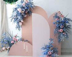 there is a pink and blue backdrop with flowers on the wall next to two candles