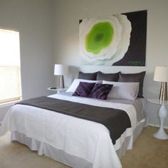 a bedroom with a large painting on the wall above the bed and two nightstands