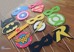 a table topped with cupcake toppers covered in batman and wonder symbols on sticks