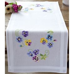 a white table cloth with purple and yellow flowers on it