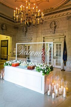 a large room with candles and flowers on the floor in front of a sign that says welcome