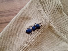 two blue bugs sitting on the side of a sweater