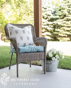 a wicker chair sitting on top of a patio next to a potted plant