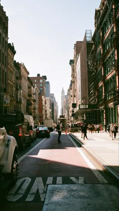 people are walking down the street in an urban area with tall buildings on either side