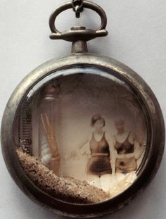 an old pocket watch with sand in it's face and two people inside the clock