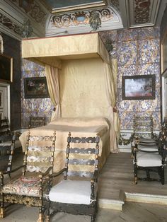 an ornate bedroom with four chairs and a canopy bed