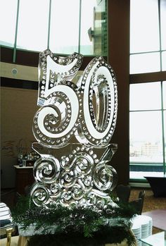 a glass cake with the number sixty on it sitting in front of some large windows