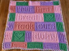 a crocheted blanket with words on it sitting on top of a wooden floor