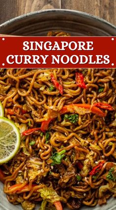 a bowl filled with noodles and vegetables on top of a wooden table next to a sign that reads singapore curry noodles