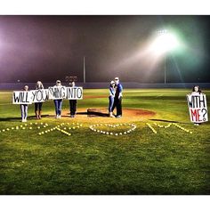 some people holding up signs in the middle of a baseball field at night with lights on