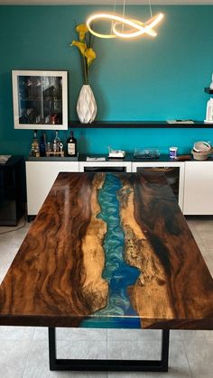 the table is made out of wood and has a river running through it in front of a blue wall