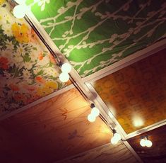 some lights are hanging from the ceiling in a room with floral wallpaper on it