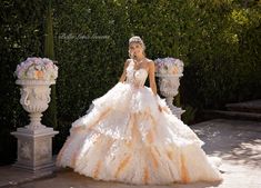 a woman in a white and orange wedding dress standing next to two large vases