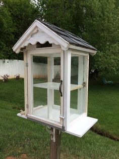 a white bird house sitting on top of a wooden pole