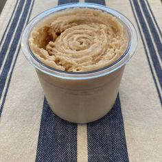 a cup filled with hummus sitting on top of a blue and white table cloth