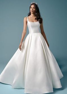 a woman in a white wedding dress with a tiara on her head, standing against a blue background