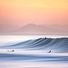 two surfers are riding the waves on their surfboards at sunset in the ocean