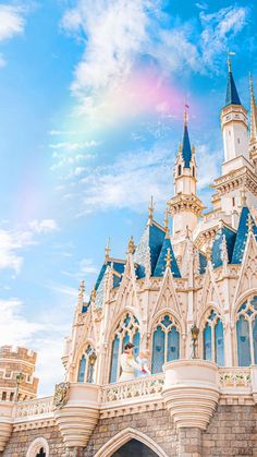 a castle with a rainbow in the background and blue sky above it, as seen from below