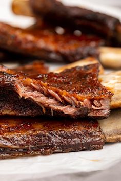 some ribs are sitting on a cutting board next to other meats and bread slices