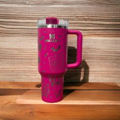 a pink travel mug with the words hope on it sitting on top of a wooden table