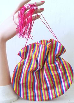 Cute vintage 1960s vibrant and colorful striped synthetic silk drawstring purse with hot pink tassels. Made of soft silk in shades of yellow, blue, green, red, hot pink, and white with silver metallic trim. The interior is lined in hot pink silk. The bottom has a structured curved base. The drawstrings pull tight to close. They have tassels at the end. Such a cute piece! The material is soft and shiny like silk, but it is a more durable synthetic silk. ☾ Info ☽Label: n/aFabric: synthetic silkCon Retro Multicolor Bags For Party, Retro Multicolor Party Bags, 60s Candy, Brown Gloves, Fabric Purse, Drawstring Purse, Fabric Purses, Colored Fabric, Pink Tassel