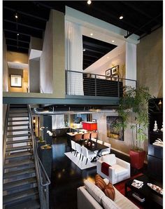 a living room filled with lots of furniture and a staircase leading up to the second floor