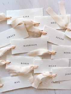 several pieces of white paper with names on them and some ribbons tied around the edges