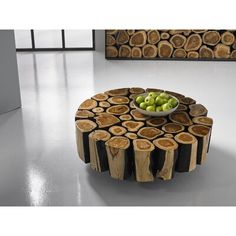 a table made out of tree slices with a bowl of green apples on the top