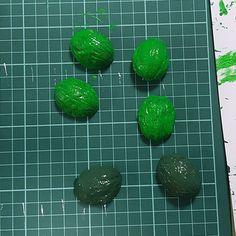 four green doughnuts sitting on top of a cutting board