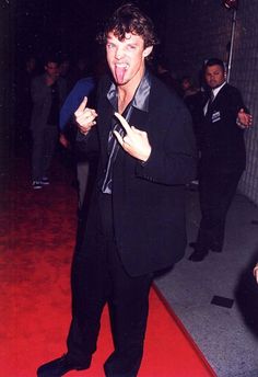 a man standing on a red carpet with his mouth open and tongue out in front of him