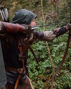 a man dressed in costume is aiming an arrow