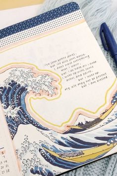 an open planner with the great wave on it and a blue pen next to it