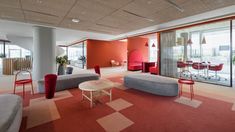 an office with red and gray chairs, couches and tables