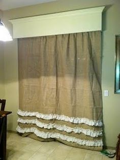 a kitchen with a table and chairs next to a curtain that has ruffles on it