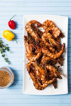 grilled shrimp on a white platter with spices and herbs next to the plate