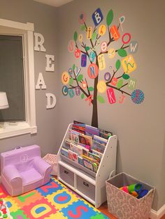 a child's playroom with toys and books on the wall, including a tree