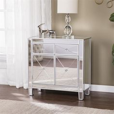 a mirrored cabinet with two drawers and a lamp on the side table next to it