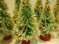 several small christmas trees in red vases on a table