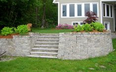 a retaining wall with steps leading up to the front door and side yard area next to it