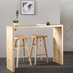 two stools and a table in a room with a painting on the wall behind it