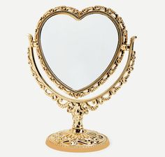 a golden heart shaped mirror sitting on top of a stand