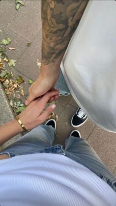 two people holding hands on the ground with leaves all around them and one person sitting down