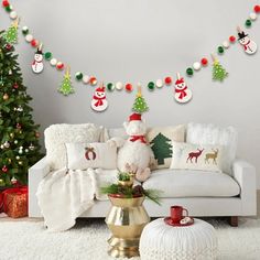 a living room decorated for christmas with decorations on the wall and white couches in front