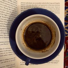 a cup of coffee sitting on top of an open book