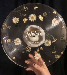 a person's hand is holding up a clear plate with flowers and words on it