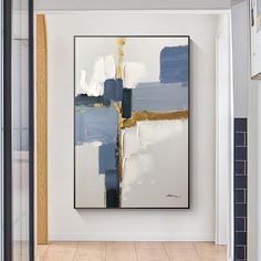 an abstract painting hanging on the wall in a white room with blue and gold accents