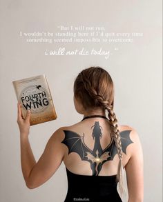 a woman holding a book in front of her back with the words fourth wing written on it